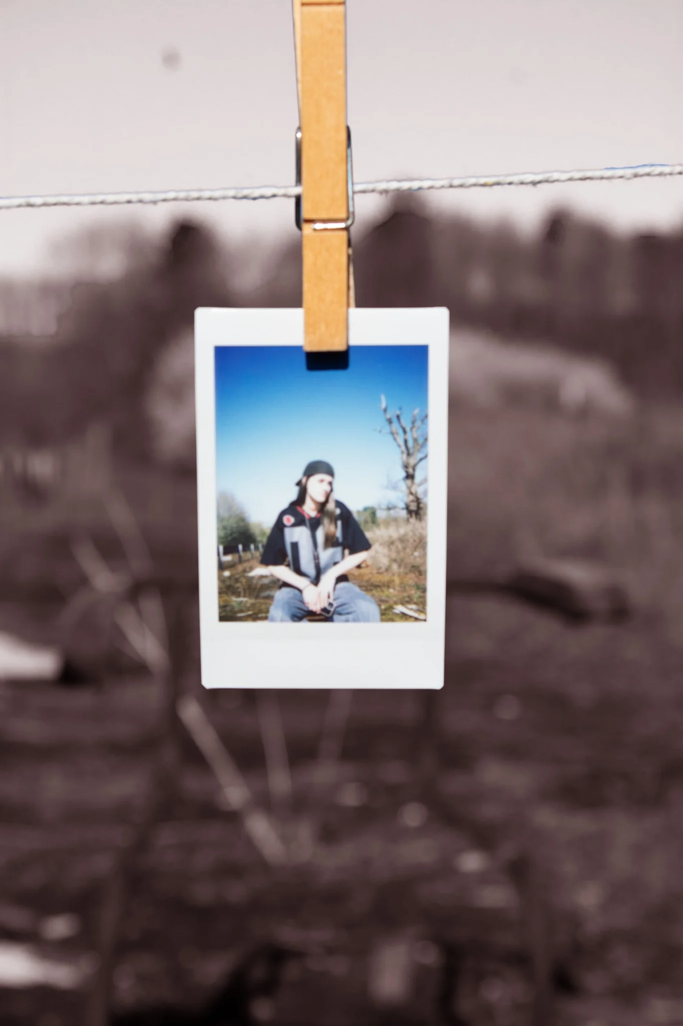 Physical Polaroid print hanging outdoors from a wooden peg
