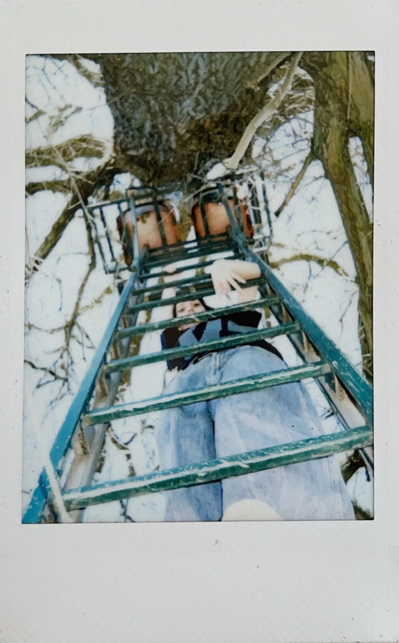 Low-angle Polaroid portrait looking upward through a metal structure