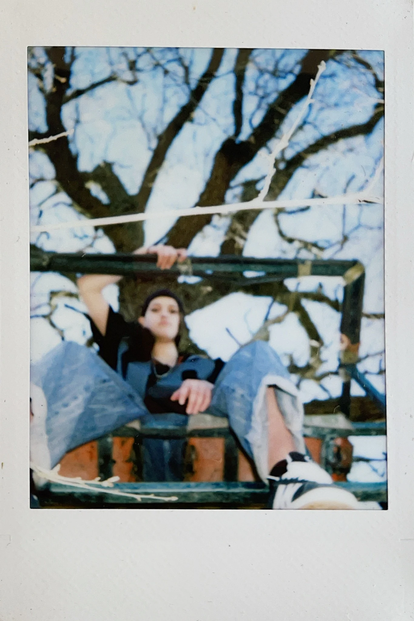 Polaroid portrait of a seated subject outdoors beneath a blue sky