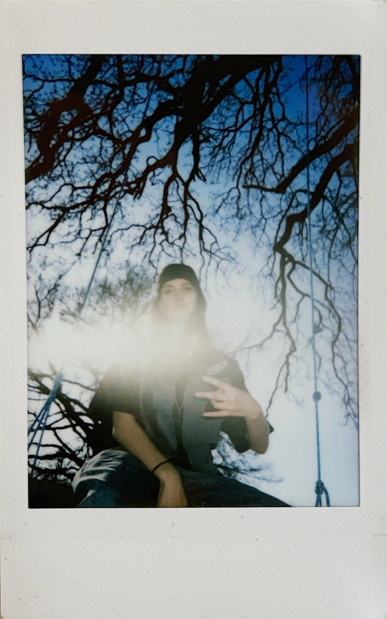 Polaroid portrait with flare and bare tree branches