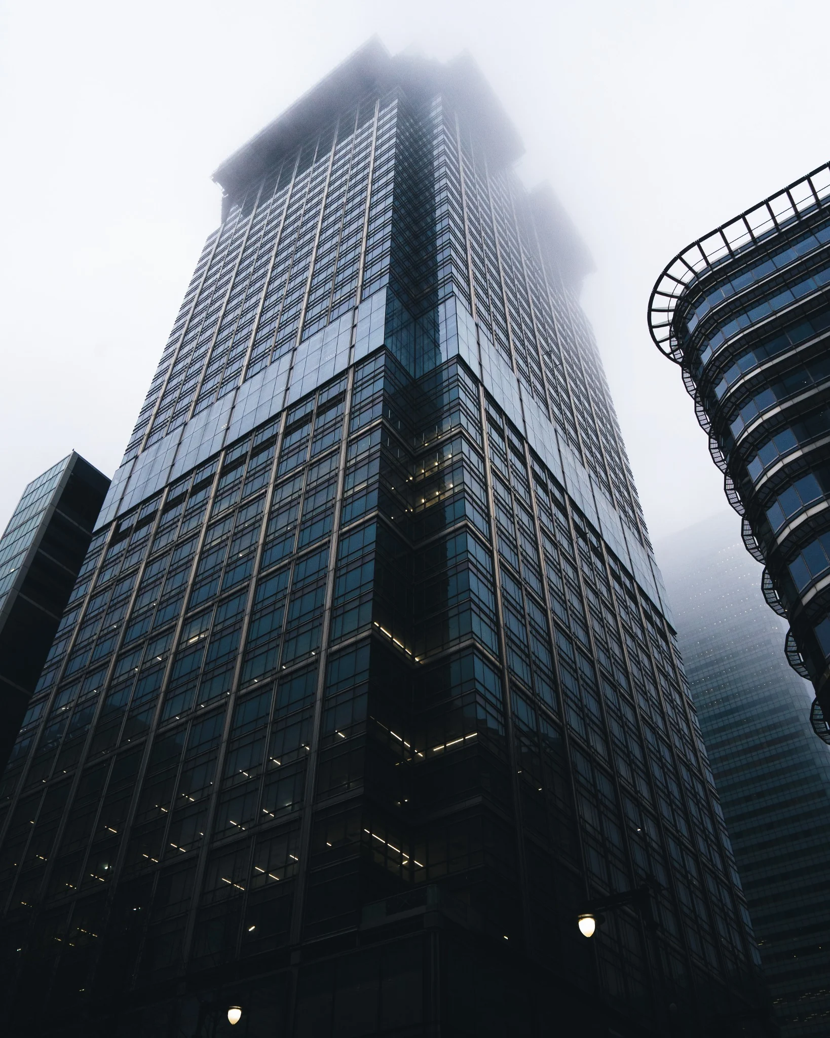 Glass skyscraper disappearing into low cloud and fog