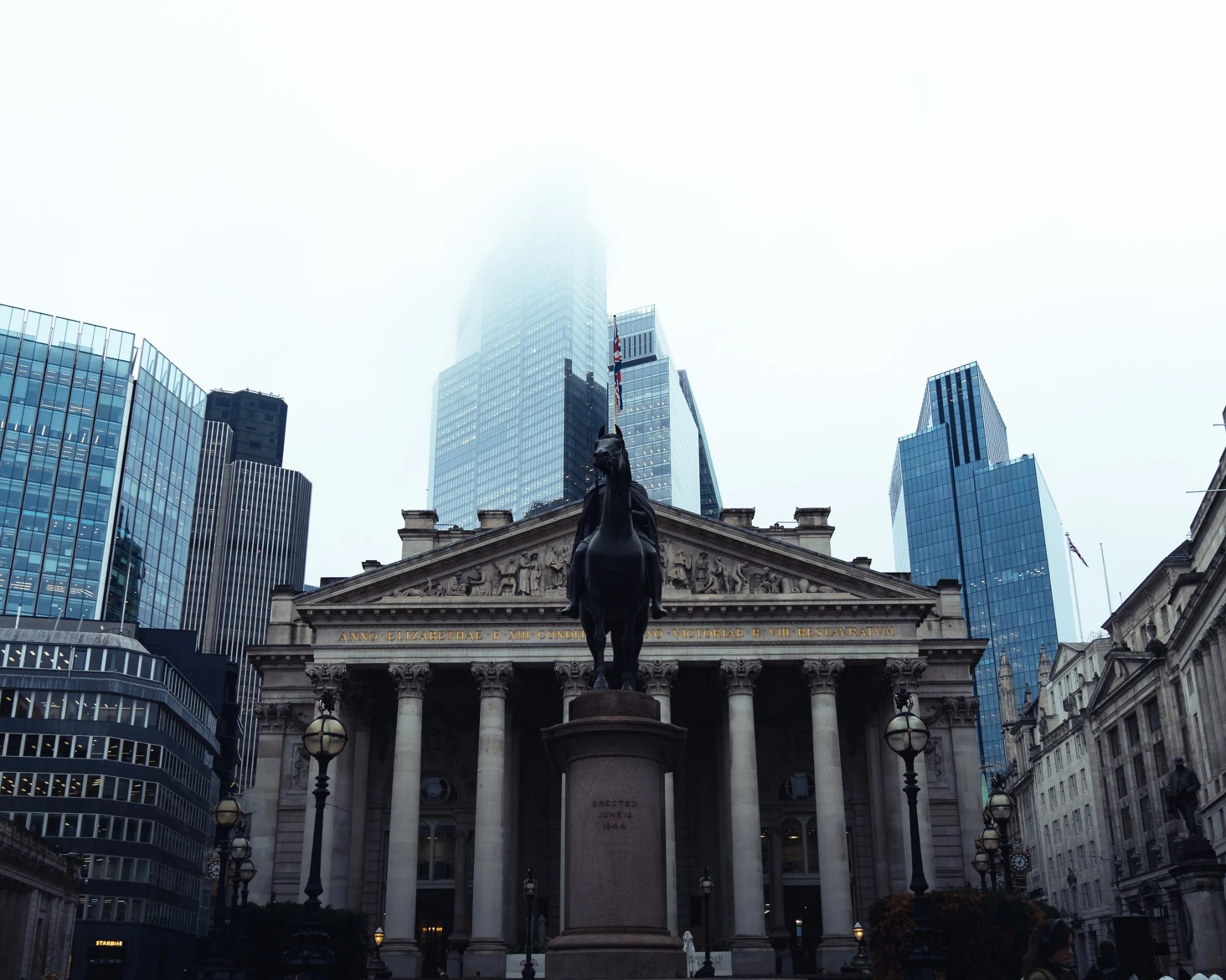 Historic London architecture framed by modern city buildings in fog