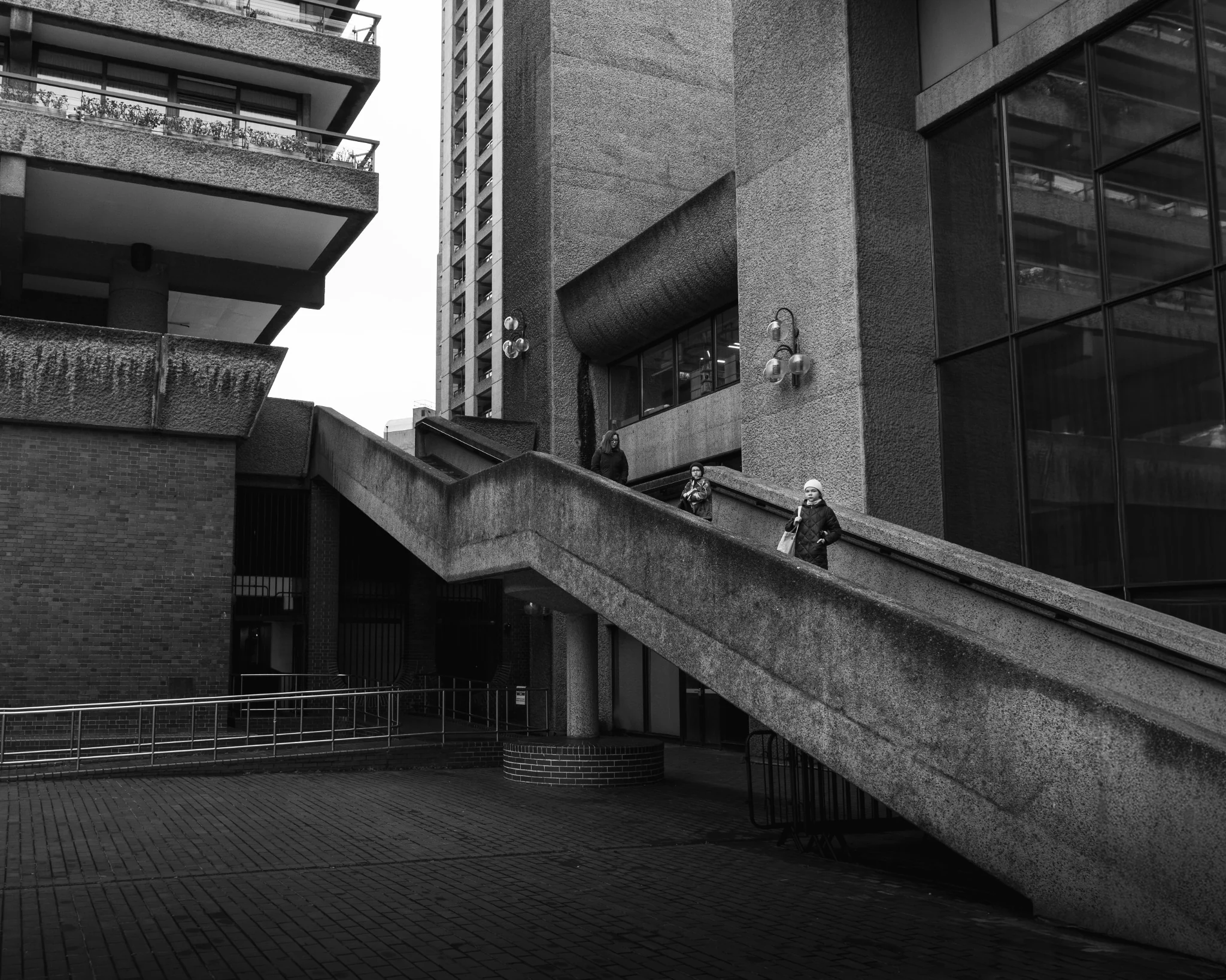 People walking along a geometric brutalist concrete walkway