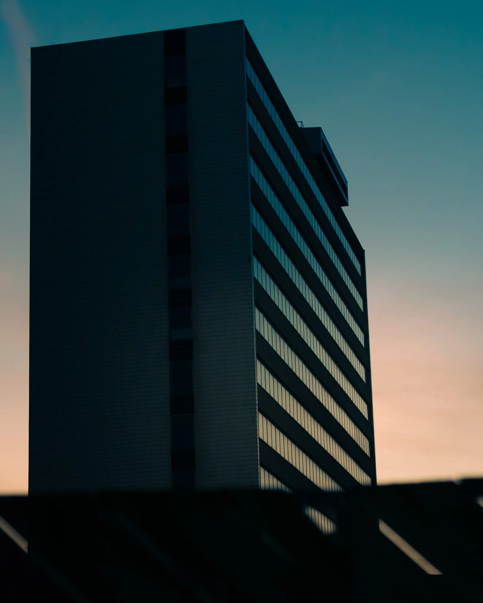 Modern office building silhouetted against a blue and pink evening sky