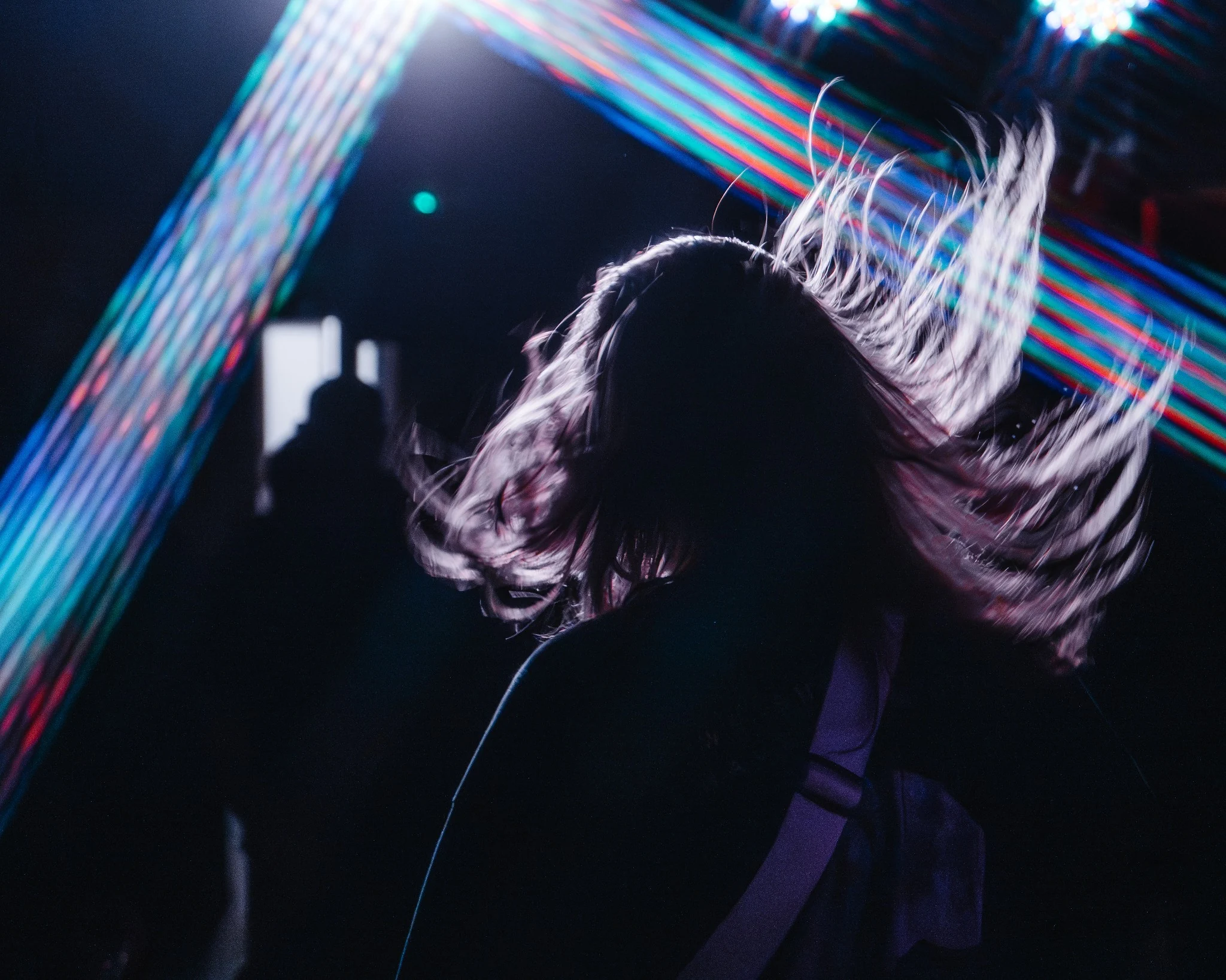 Performer captured with hair movement and coloured stage light trails