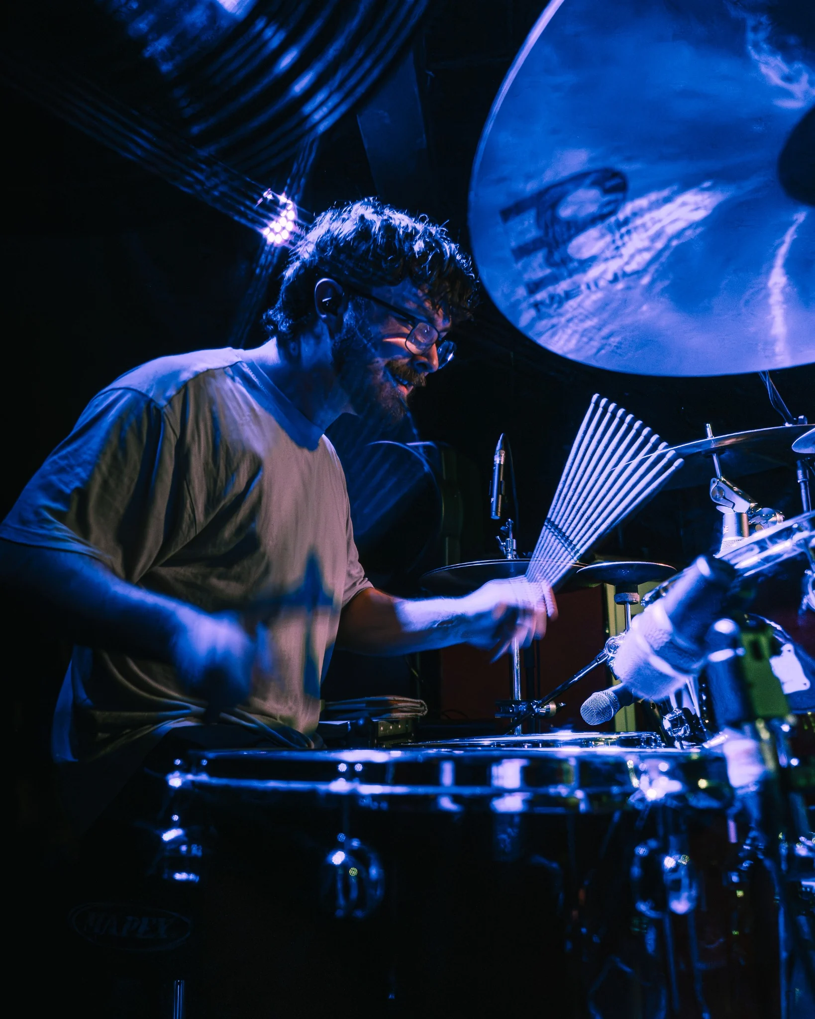 Drummer performing under deep blue stage lighting