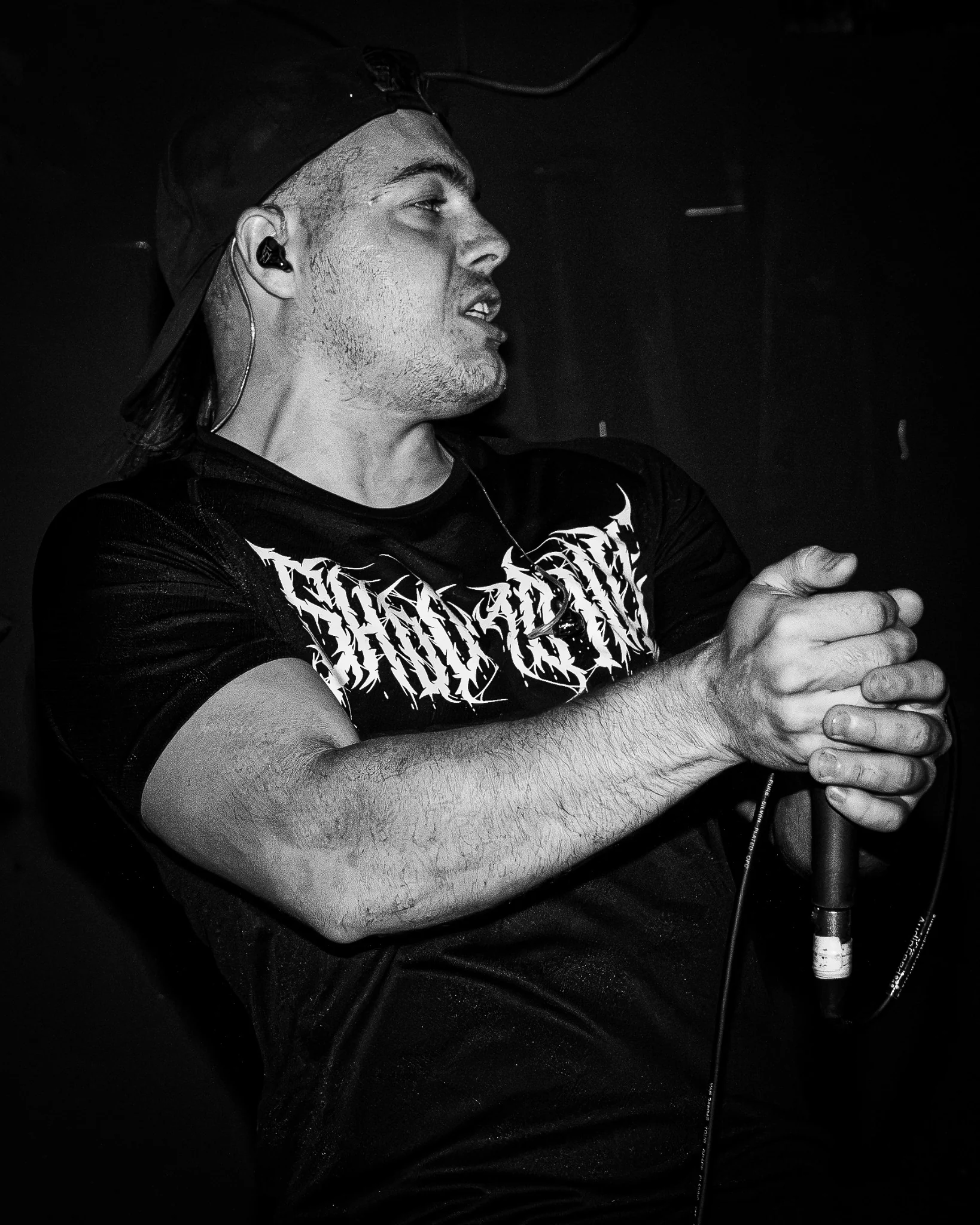 Black and white close portrait of a vocalist holding a microphone