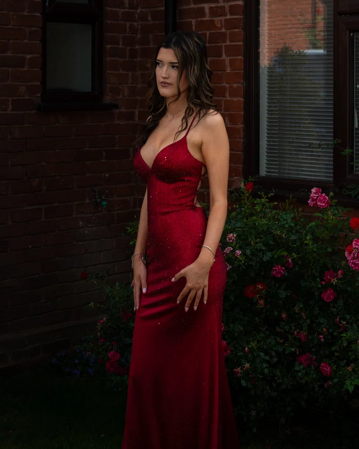 Individual prom portrait in a red dress beside garden roses