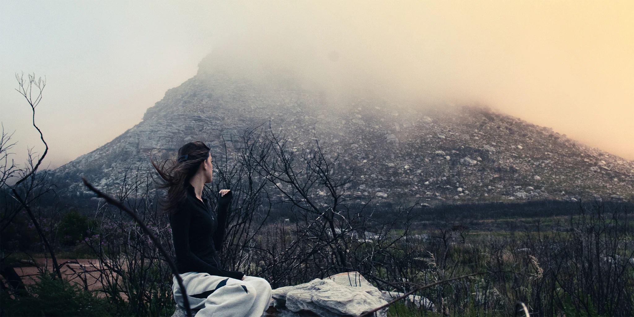 Figure seated in a misty mountain landscape